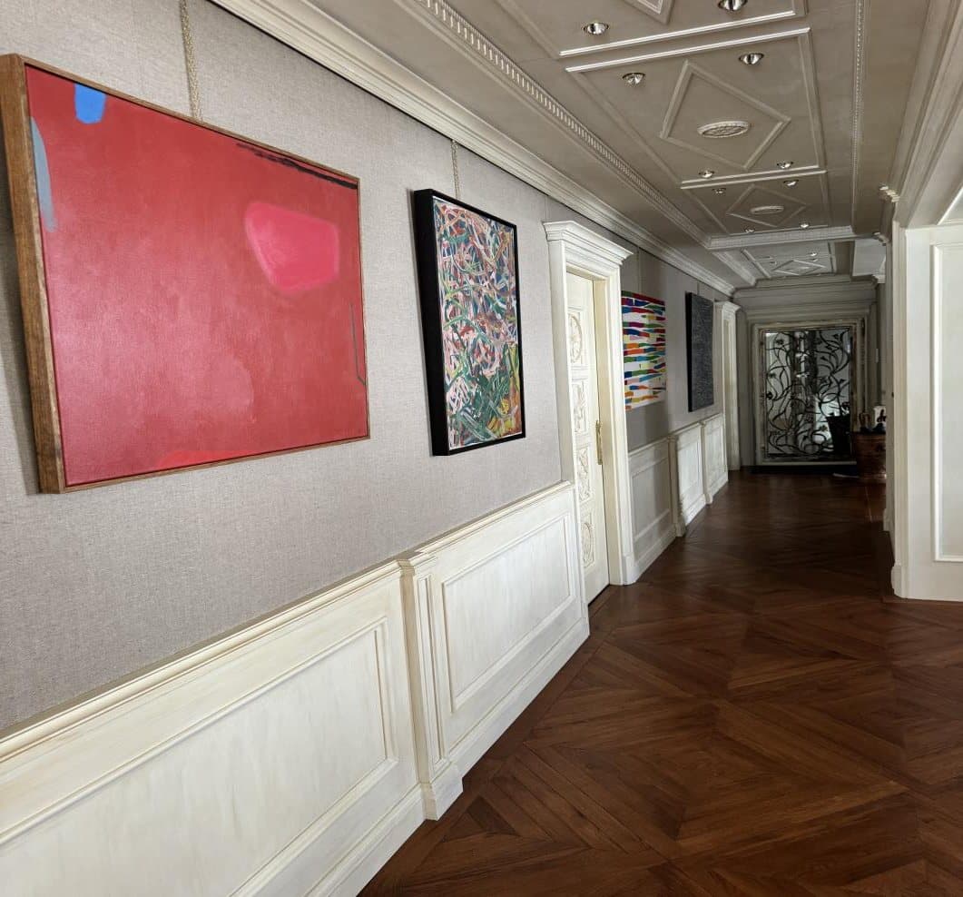 A gallery hallway of contemporary art connects the rooms.